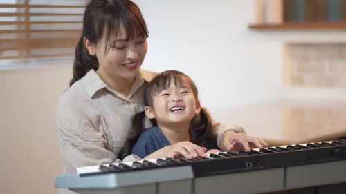Woman and Child Play Piano Keyboard Together Indoors