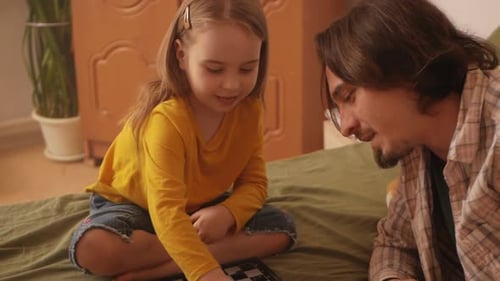 Father and Daughter Play Checkers at Home