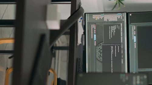 Mesa de vídeo vertical vazia com vários monitores exibindo o código do servidor e a linguagem de programação