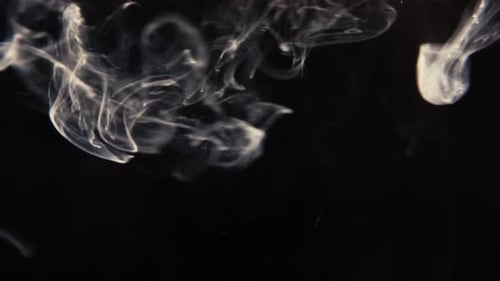 White paint dissolving in water with dark background, shot in studio with Sony a7iii.