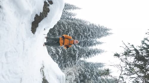 Man Hiking Through a Snowy Forest in Winter