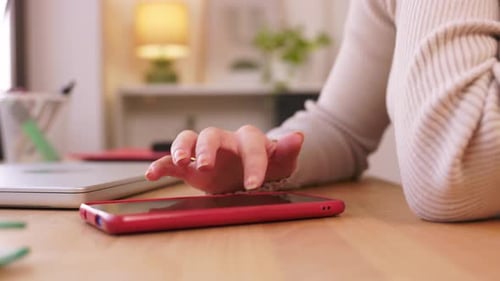 Unrecognizable Young Woman Browsing on Smartphone at Home Office Desk