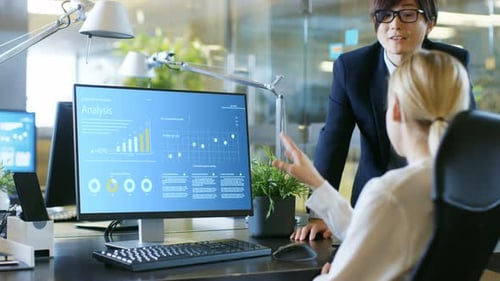 In the Office Businesswoman Sitting at Her Desk Talks with Her Manager about Statistical Growth Sho