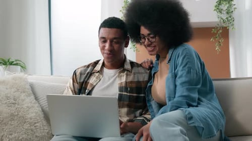 Couple Using Laptop Together on Couch Indoors