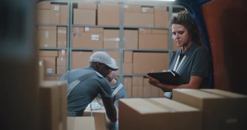 Multiethnic Workers Unloading Cardboard Boxes Female Manager Using Tablet Computer and Scanner