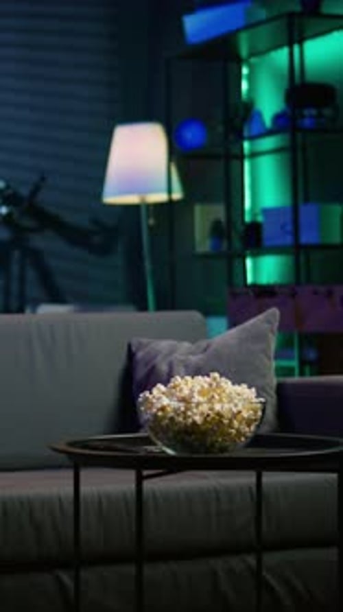 Vertical Video Bowl of Popcorn on Table in Neon Illuminated Home Theater Apartment