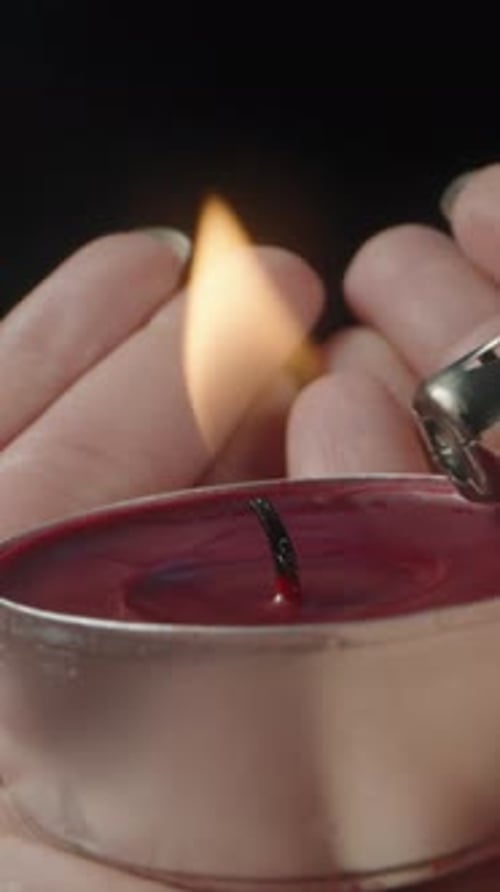 I light a red candle in the girl's palms, close-up.Vertical video Social Media