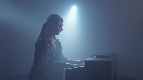 Elegant Woman Plays Piano in Foggy Studio