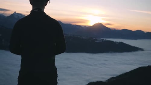 Mann-Silhouette, die auf einem Berg steht und die wunderschönen Sonnenuntergangswolken über dem Meer in Ch beobachtet