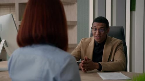 Un homme d'affaires afro-américain, directeur des ressources humaines, consultant et agent de vente, parle à une cliente au bureau