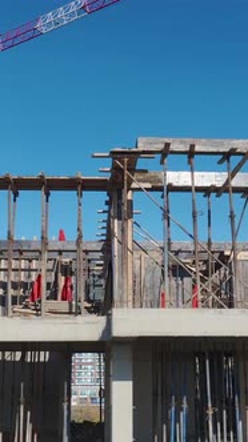 Vertical Video Construction Activity From the Air Shows Workers and Cranes on a New Project Site