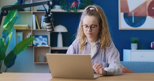 Woman Works on Laptop at Desk with Microphone