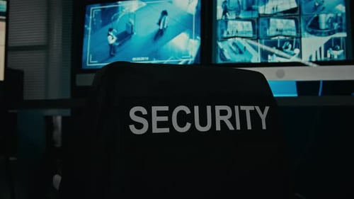 Security Guards Uniform Jacket on Chair in front of CCTV Screens in Control Room
