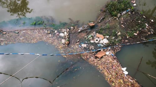 Über einem Fluss befestige Netzfalle für die Müllabfuhr. Zeitraffer mit reflektierenden Wolken und dem Massenkrieg