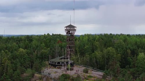 Tourists Admiring Stunning Vistas From a Wooden Lookout Tower Surrounded By Vibrant Green Forests
