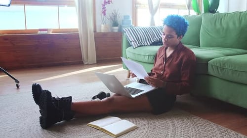 Young African American Woman Freelancer Sits on Floor with Laptop on Knees