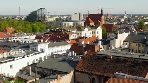 Aerial trucking shot over cityscape of Bydgoszcz with cathedral and modern tall buildings during sun