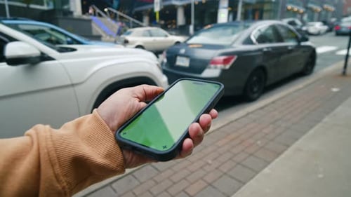 Man Holding Smartphone With Green Screen Chroma Key On City Street Background