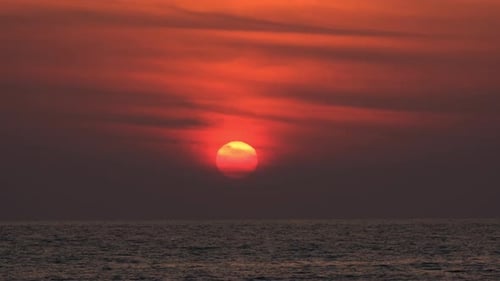 Dramatic sunrise with orange sky in a cloudy day at the ocean.