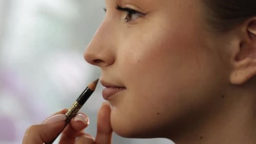 Maquilleur professionnel appliquant un crayon à lèvres nude