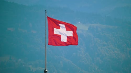 Swiss flag waves atop mountain with green background