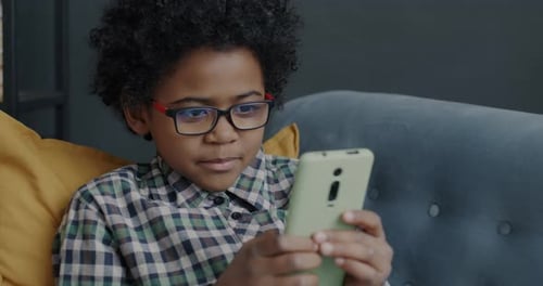Boy Using Smartphone on Couch Indoors