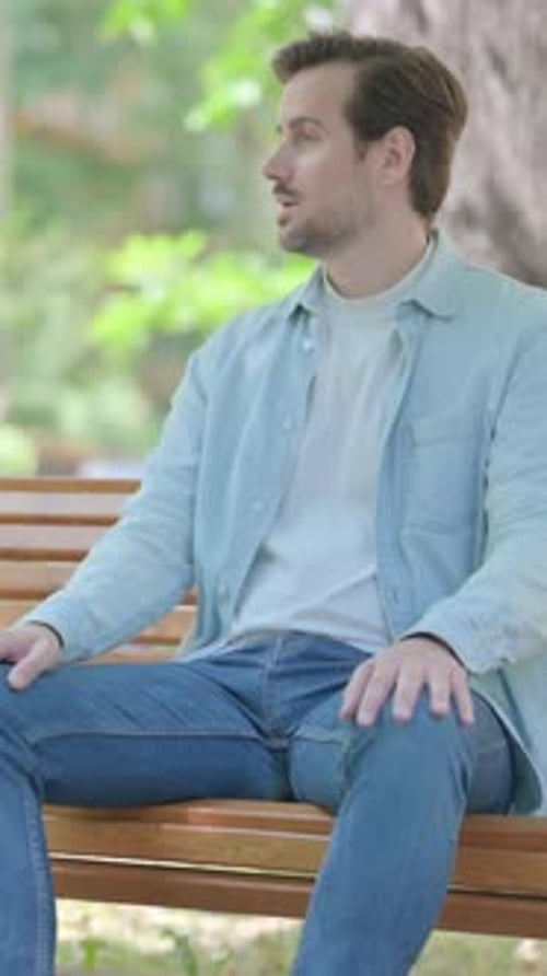 Man Sitting Calmly on Park Bench on Sunny Day