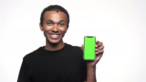 Smiling Man Holding Smartphone with Green Screen Thumbs Up Gesture