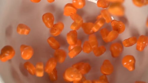Close up of orange skulls shaped candy falling on a plate.