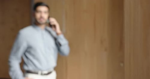 Talking on smartphone, businessman in office, wearing casual business attire