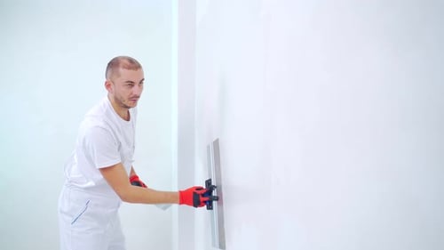 Man Plastering a White Wall With Trowel