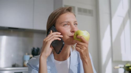 Joyful Woman Talking Smartphone at Home Closeup Relaxed Lady Eating Green Apple