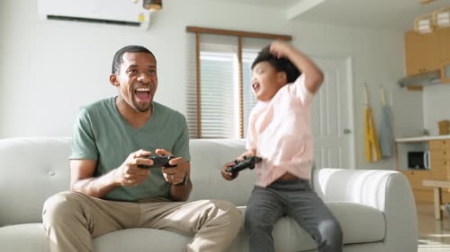 Father and Son Play Video Games Together at Home