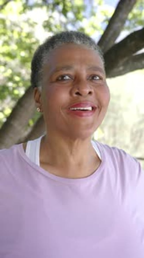 Vertical video portrait of happy senior african american woman in sunny nature, slow motion