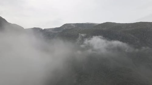 High altitude flying through cloudscape revealing majestic mountain landcape