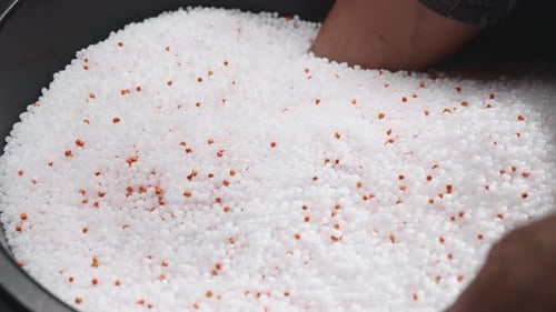 A Woman Mixes Plastic Granules with Orange Pigment to Create Colored Plastic Polymer Composites are