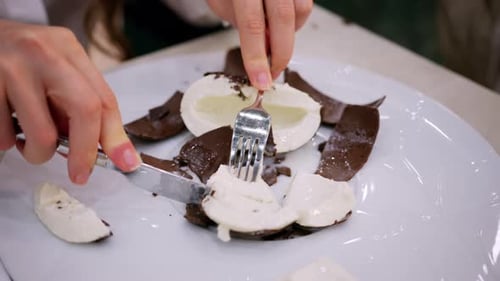 Close up of a dessert shaped like a coconut being opened with a fork, revealing a creamy white inter