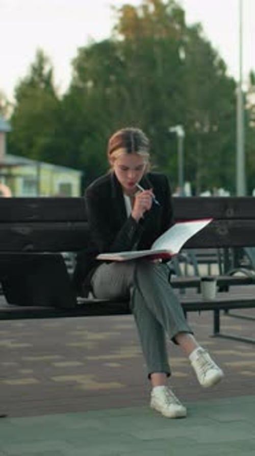 Thoughtful Woman Studies Documents on Park Bench