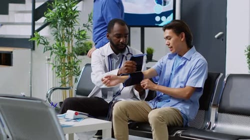 Doctor Checking Young Man's Blood Pressure at Clinic