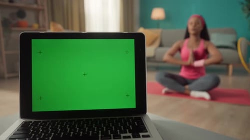 A Laptop with a Green Screen on a Table Against a Blurred Background in a Room Close Up In the