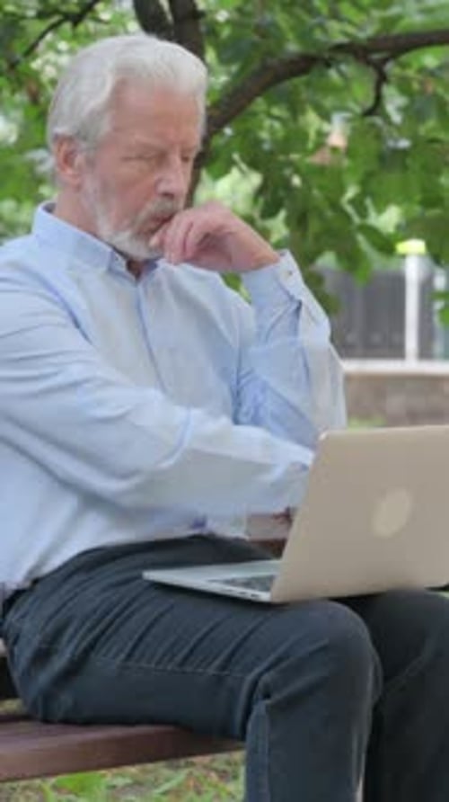Senior Man Working on Laptop While Seated Outdoors