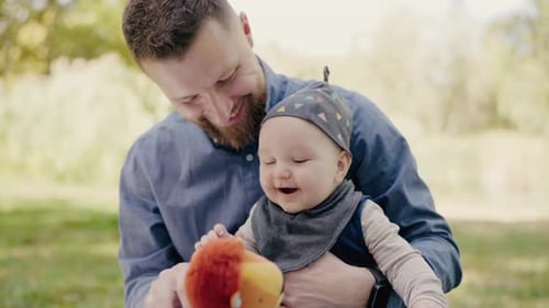 Loving Father Entertaining Baby with Toy Outdoors