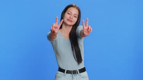 Smiling Woman Making Peace Sign on Blue Background