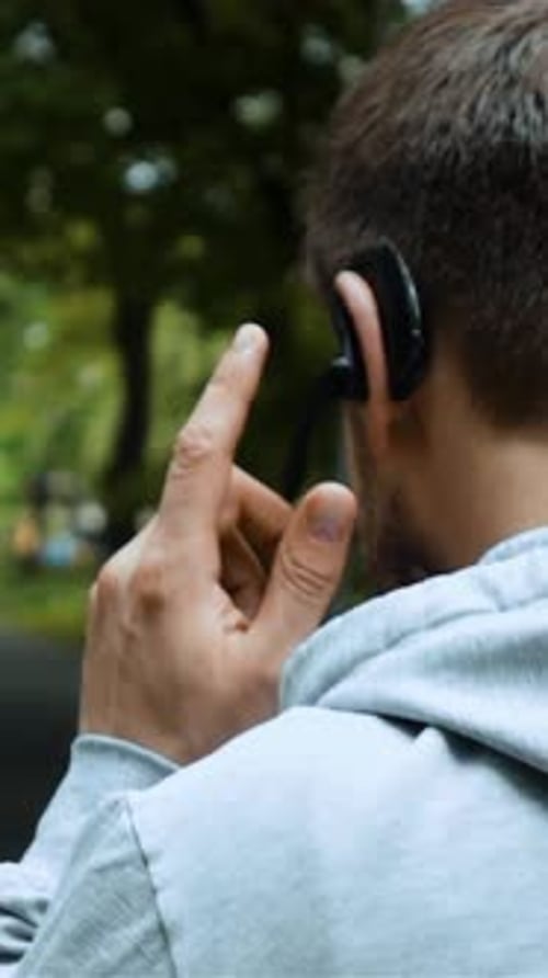 Vertical of Road Runner Talking By Phone with Bluetooth Headset in Autumn Park