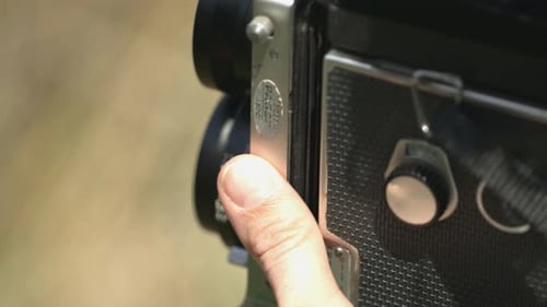 Une main tient un appareil photo vintage en gros plan.