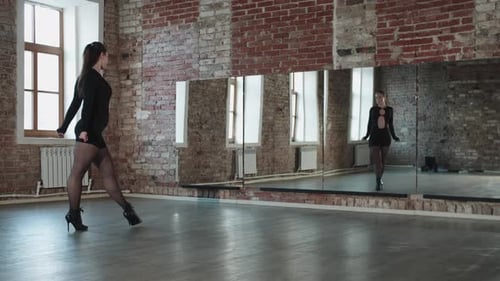 An Attractive Woman in a Sexy Black Outfit Practicing Her Dancing in Front of a Mirror in the Studio