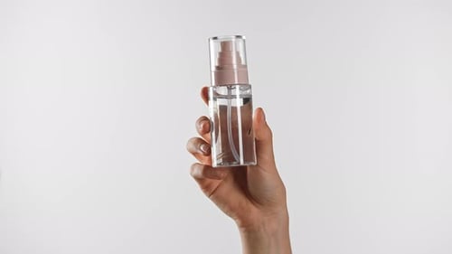 Hand Showcases Clear Bottle Against White Background