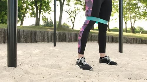Woman Squats with Resistance Band in Outdoor Gym