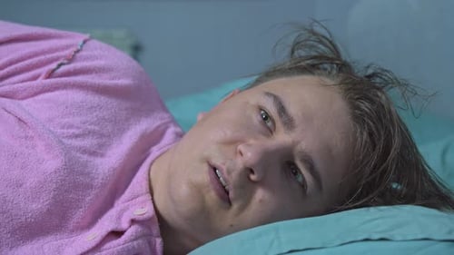 L'homme dort dans son lit, se réveille à cause du bruit, regarde autour de lui Anxiété, dormeur léger