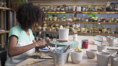 African woman make earth ware at workshop.